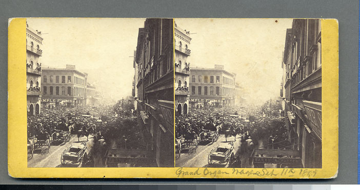 Watkins Unnumbered View - Grand Organ Wager Sept 11, 1867 - (handwritten on back) Sept 11, 1867 A.N(.?) Higgins marched along Montgomery playing hand organ to fulfill wager on election; Jones Sample Rooms, California & Montgom